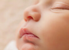 This is a close-up of a sleeping baby’s face. They look calm and peaceful.