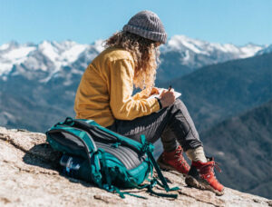 Woman writing in notebook on a mountain